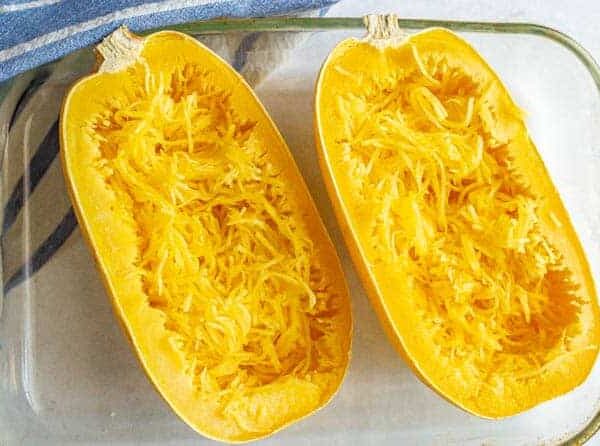The contents of a clear glass baking dish, featuring two halves of squash spaghetti with shredded flesh inside, bring to mind the lush greens found in a Squash 'Spaghetti' 4" Pot.