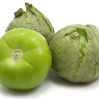 Three tomatillos, with two partially in husks, are set against a white background.