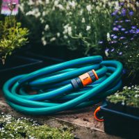 A Hose with Fittings and Tap Connectors 18mmx10m laying on a wooden bench.