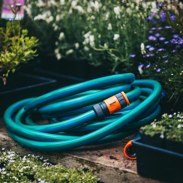 A Hose with Fittings and Tap Connectors 18mmx10m laying on a wooden bench.