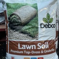 A 25L bag of Debco Lawn Soil 25L, labeled as premium top-dress and underlay soil. The packaging showcases a rolled-up piece of turf and highlights features like slow-release fertilizer.