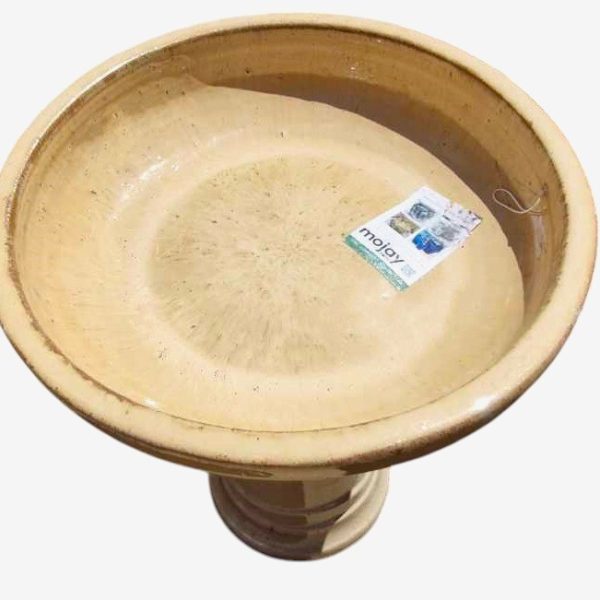 A round, beige birdbath filled with water, featuring a Sorrento Birdbath Cream 46x60cm label inside.