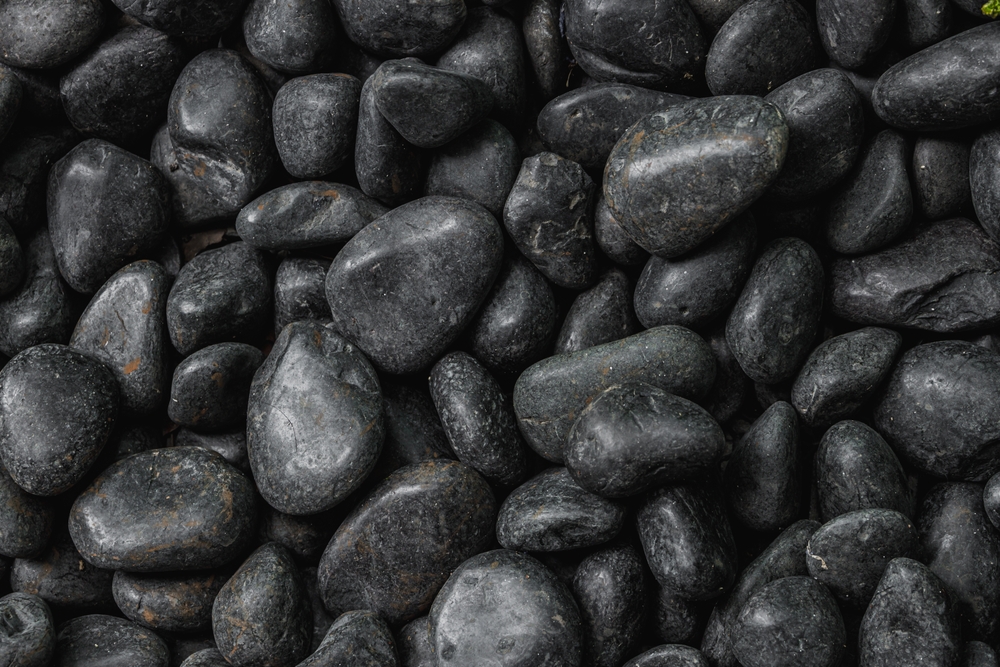 A close-up view of Pebbles Black 30-50mm from a 20kg bag, tightly packed together and highlighting their smooth, polished surfaces.