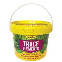A yellow plastic tub labelled "Searles Trace Elements" with a white handle, used for correcting plant nutrient deficiencies and boosting growth.