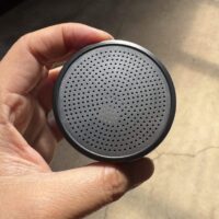 A hand holds the Hose Nozzle Water Breaker 400 Hole—black plastic head only—with a round, perforated front grille resembling its unique nozzle pattern.