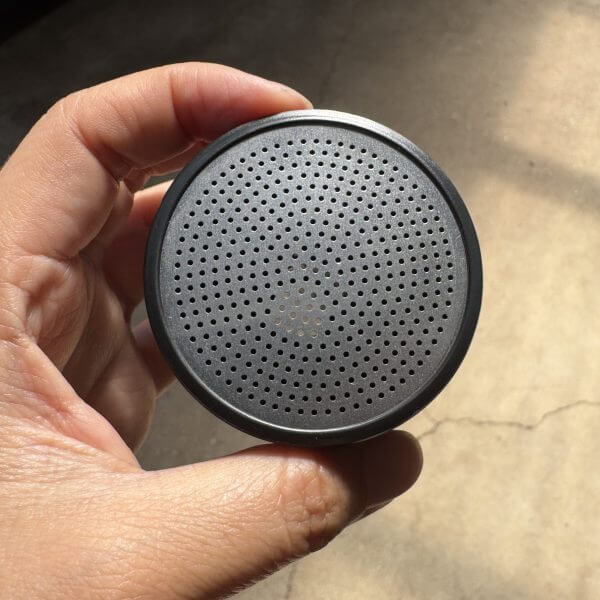 A hand holds the Hose Nozzle Water Breaker 400 Hole—black plastic head only—with a round, perforated front grille resembling its unique nozzle pattern.