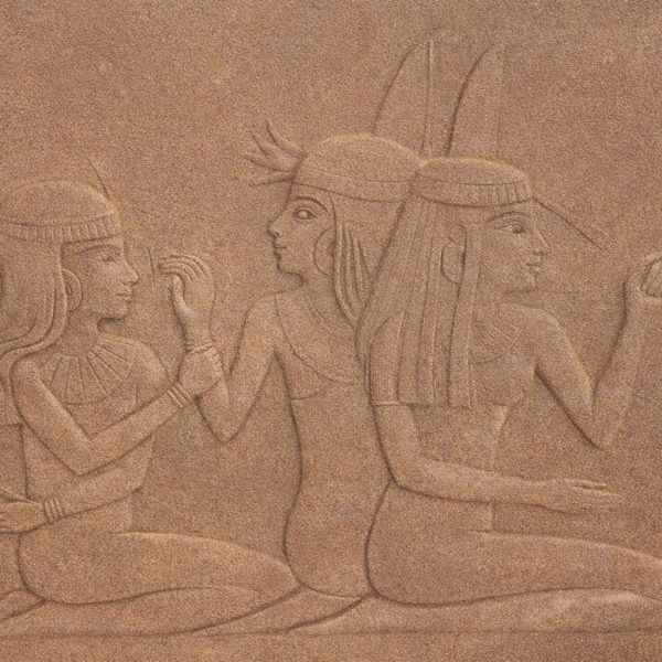 Stone relief depicting three seated ancient Egyptian women, each wearing traditional headdresses and garments, with one woman gesturing and the others engaged in conversation.